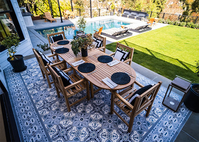 Teak family table and teak chairs outside on the patio.